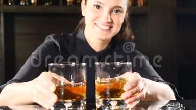 夜总会里的夜生活。 女酒吧员把酒精鸡尾酒放在酒吧柜台的酒杯里。 酒吧和鸡尾酒概念